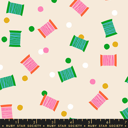 Spools in Shell quilting cotton by Ruby Star Society — spools of thread tossed across the cloth in a rainbow of colours on a soft blush pink — pattern repeat