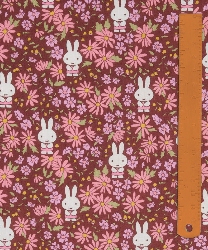 Liberty x Miffy Prairie Day Tana Lawn in deep burgundy, with pink and coral daisies, shown with a ruler for scale