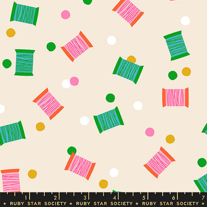 Spools in Shell quilting cotton by Ruby Star Society — spools of thread tossed across the cloth in a rainbow of colours on a soft blush pink — pattern repeat